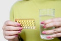 Woman hand taking birth control or contraceptive pills with glass of water Royalty Free Stock Photo