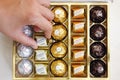 Woman hand taking candy Ferrero Tenderly from box of Ferrero can