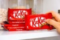 Woman hand taking KitKat chocolate bar by Nestle from shelf of kitchen cupboard