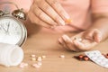 Woman hand taking pills with glass of water and clock on desk, Royalty Free Stock Photo