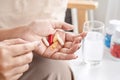 woman hand taking supplementary food, vitamins c, b, fish oil and a glass of water on a table