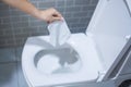 Woman hand throw paper towels in the toilet bowl. Cleaning, Lifestyle and personal hygiene concept Royalty Free Stock Photo