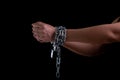 Woman hand tied up with steel chain and lock at the black background, Human rights violations and International women`s Day