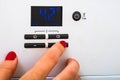 Woman hand try to turn off and on the central heating in the room. Female hands on the central heating control panel. Girl hand Royalty Free Stock Photo