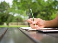 Woman hand use green pencil writing on white notebook on table in green natural park. Think out side the box and generate idea in Royalty Free Stock Photo