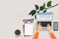 Woman hand using laptop with copy space of white working table with lnote book, pencil, smartphone, cup of coffee and eye glasses