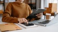Woman hand using a laptop, smartphone and tablet and a calculator to calculate the numbers, finance at the office of her business Royalty Free Stock Photo