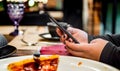 Woman hand using mobile phone in cafe with a piece of pizza in plate Royalty Free Stock Photo