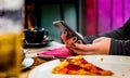 Woman hand using mobile phone in cafe with a piece of pizza in plate Royalty Free Stock Photo