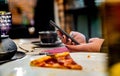 Woman hand using mobile phone in cafe with a piece of pizza in plate Royalty Free Stock Photo