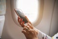 Woman hand using smart phone on airplane. Female traveler using Royalty Free Stock Photo