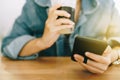 Woman hand using smartphone while drinking coffee with cafe shop colorful highlight shade to object beautiful backgroun Royalty Free Stock Photo