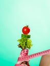 Woman hand with vegetarian food and measuring tapes.