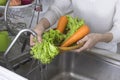 Woman hand washing organic lettuce and carrots vegetables in the kitchen