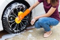 Woman hand wearing orange gloves with yellow sponge washing wheel modern car or cleaning automobile. Royalty Free Stock Photo