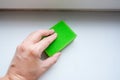 Woman hand wiping dust from a window sill with a sponge, cleaning and tiding up the house every day