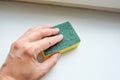 Woman hand wiping dust from a window sill with a sponge, cleaning and tiding up the house every day