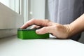 Woman hand wiping dust from a window sill with a sponge, cleaning and tiding up the house every day