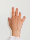 Woman hand wrist wearing golden hand chain set against a white background Royalty Free Stock Photo