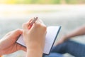 Woman hand writing down in small white memo notebook Royalty Free Stock Photo