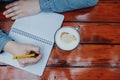 Woman hand writing journal on small notebook while drinking coffee, top view