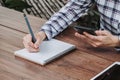 Woman hand writing notepad and holding phone on wooden table at coffee shop Royalty Free Stock Photo