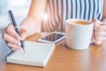 Woman hand is writing on a notepad with a pen on a wooden desk Royalty Free Stock Photo