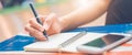 Woman hand is writing on a notepad with a pen on wooden desk. Royalty Free Stock Photo