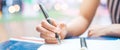 Woman hand is writing on a notepad with a pen on wooden desk Royalty Free Stock Photo