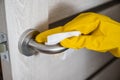 Close up woman hand in yellow latex cleaning gloves spraying antiseptic spray on the door handle. Door disinfection Royalty Free Stock Photo