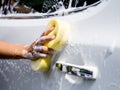Woman hand with yellow sponge washing car Royalty Free Stock Photo