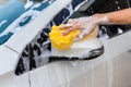 Woman hand with yellow sponge washing side mirror modern car or cleaning automobile. Royalty Free Stock Photo
