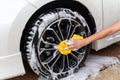 Woman hand with yellow sponge washing wheel modern car or cleaning automobile.