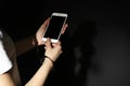 Woman in handcuffs using smartphone on black background, closeup. Solitude concept