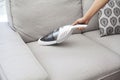 Woman with handheld vacuum cleaning on sofa Royalty Free Stock Photo