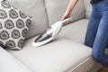 Woman with handheld vacuum cleaning on sofa Royalty Free Stock Photo