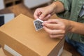 woman hands affix QR code sticker to package, e-commerce delivery and online shopping