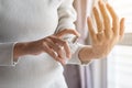 Woman hands applying bottle of her favorite perfume at home