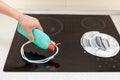 Woman hands with bottle of cleaning detergent for induction stove applies a liquid scour to the burner Royalty Free Stock Photo