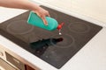 Woman hands with bottle of cleaning detergent for induction stove applies a scour to the burner Royalty Free Stock Photo