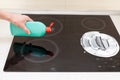 Woman hands with bottle of cleaning detergent for induction stove applies a scour to the burner Royalty Free Stock Photo