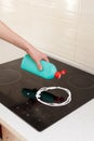 Woman hands with bottle of cleaning detergent for induction stove applies a scour to the burner. House cleaning. Royalty Free Stock Photo