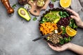 Woman hands with bowl of delicious quinoa salad with avocado, sweet potato, beans on gray background. superfood concept. Healthy, Royalty Free Stock Photo