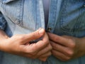 A woman hands buttoning a light blue denim jacket