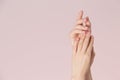 Woman hands with clean skin and nails with pink polish manicure on pink background. Nails care and beauty theme.
