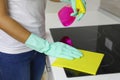 Woman hands cleaning a modern black induction hob by a rag and spray