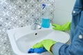 Woman hands cleaning and polishing wash basin and faucet in bathroom