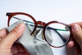 Woman hands cleaning shortsighted or nearsighted eyeglasses by microfibre cleaning cloths, On white background, Optical concept