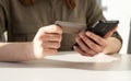 Woman hands closeup holding credit card and phone. Woman sitting at table and paying in application, shopping online or Royalty Free Stock Photo