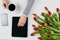 Woman hands with computer tablet, cup of coffee, mobile phone and beautiful flowers bunch on the white office table Royalty Free Stock Photo